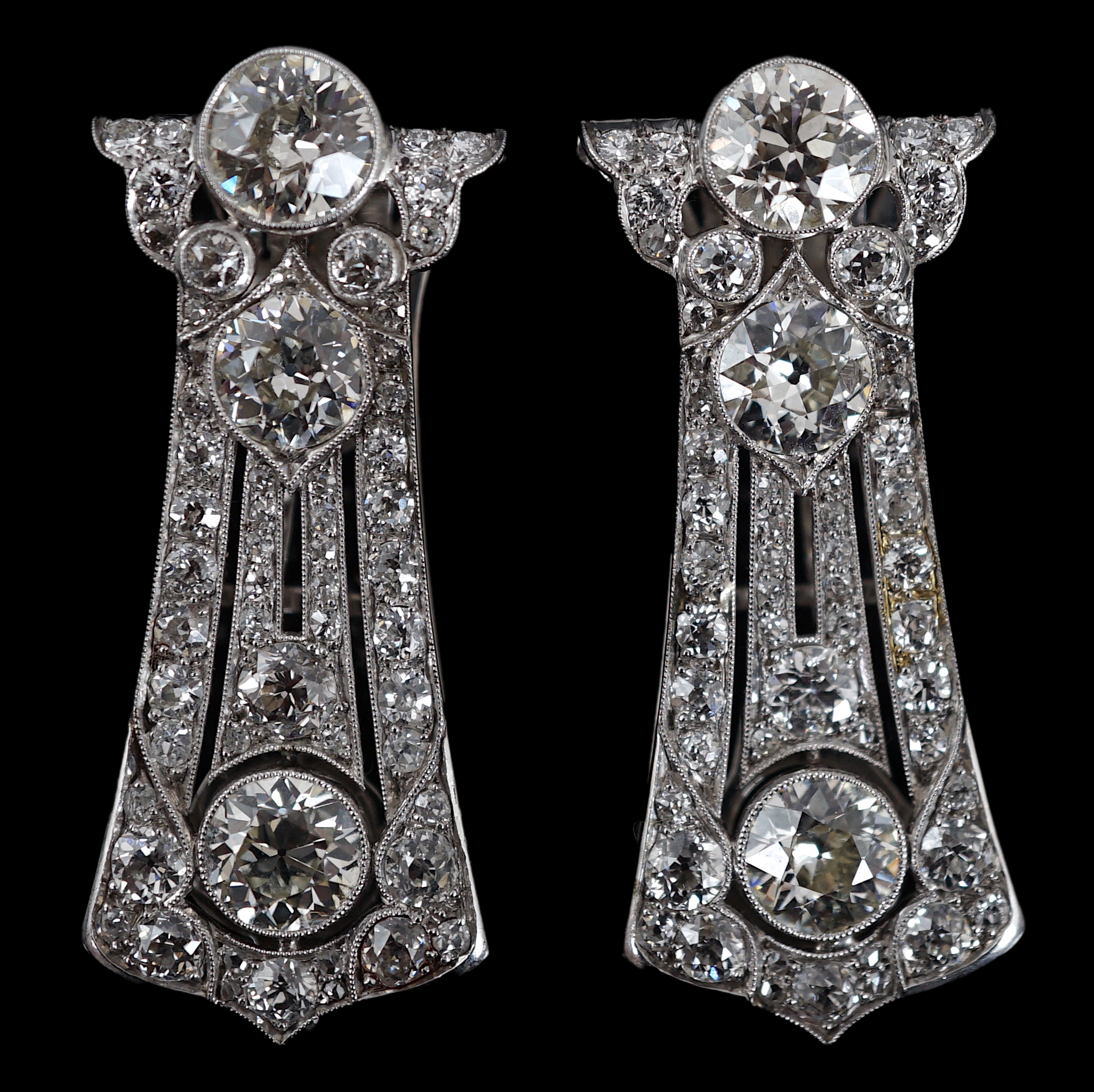 A pair of Art Deco white gold and round cut millegrain set diamond cluster clip brooches